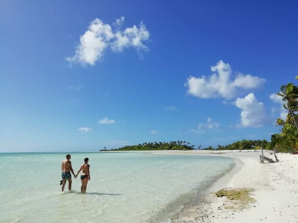 Couple dans le lagon au bord d'une plage blanche de Tetiaroa